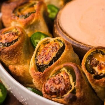 Close-up of jalapeño popper rolls in a bowl, served with a side of creamy dipping sauce.