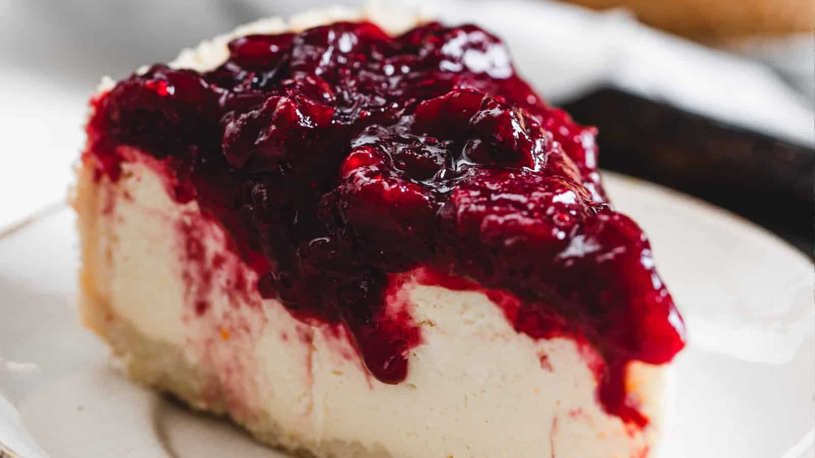 A slice of cheesecake topped with thick, glossy cherry sauce on a white plate—a classic favorite among Shavuot cheese recipes.