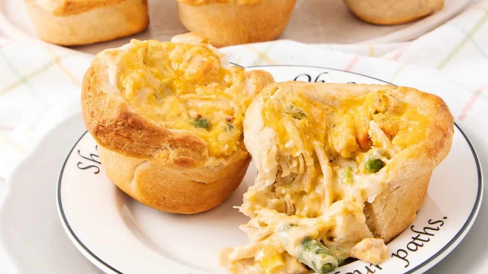 Two mini chicken pot pies on a plate, one split open to show the creamy chicken and vegetable filling.