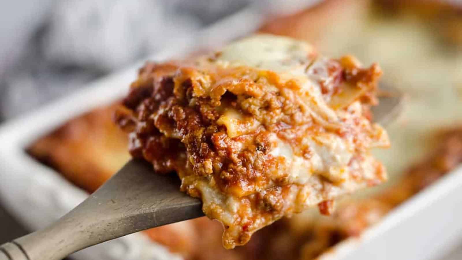 Slice of layered lasagna with melted cheese and rich meat sauce.