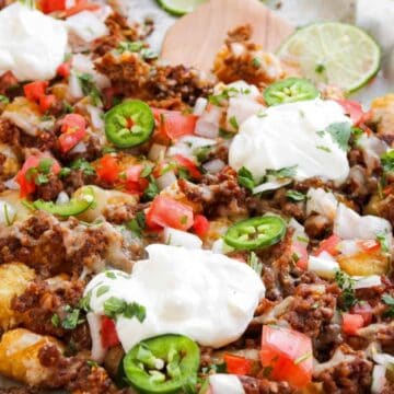 Tater tots topped with ground beef, cheese, tomatoes, onions, jalapeños, and dollops of sour cream.