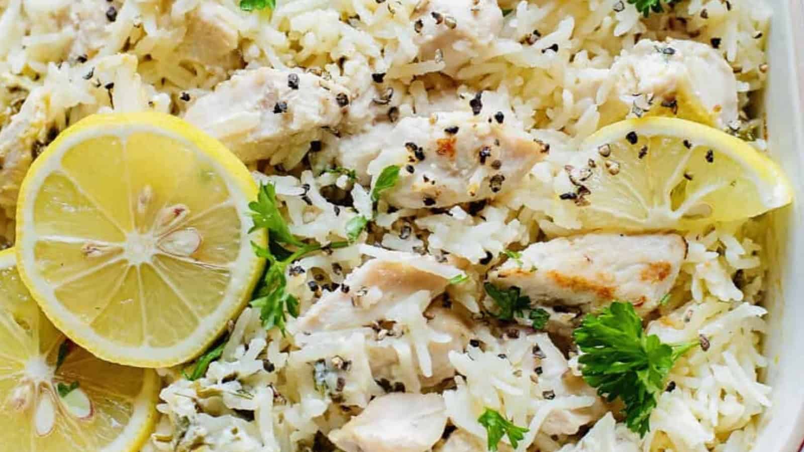 Rice and chicken dish garnished with lemon slices, parsley, and cracked black pepper.