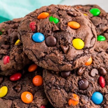 A plate of chocolate cookies topped with colorful candy-coated chocolates and chocolate chips.