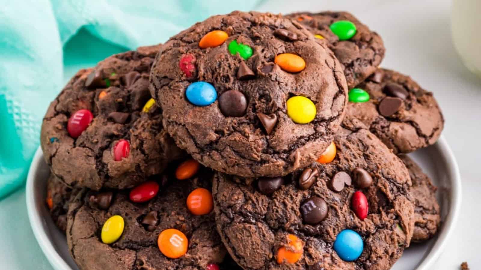 A plate of chocolate cookies topped with colorful candy-coated chocolates and chocolate chips.