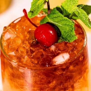 A glass filled with crushed ice, garnished with a cherry and fresh mint leaves.