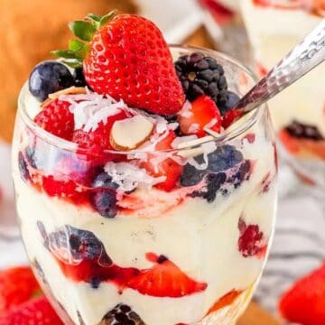 Delicious berry parfait topped with strawberries, blueberries, and blackberries, served in a glass w.