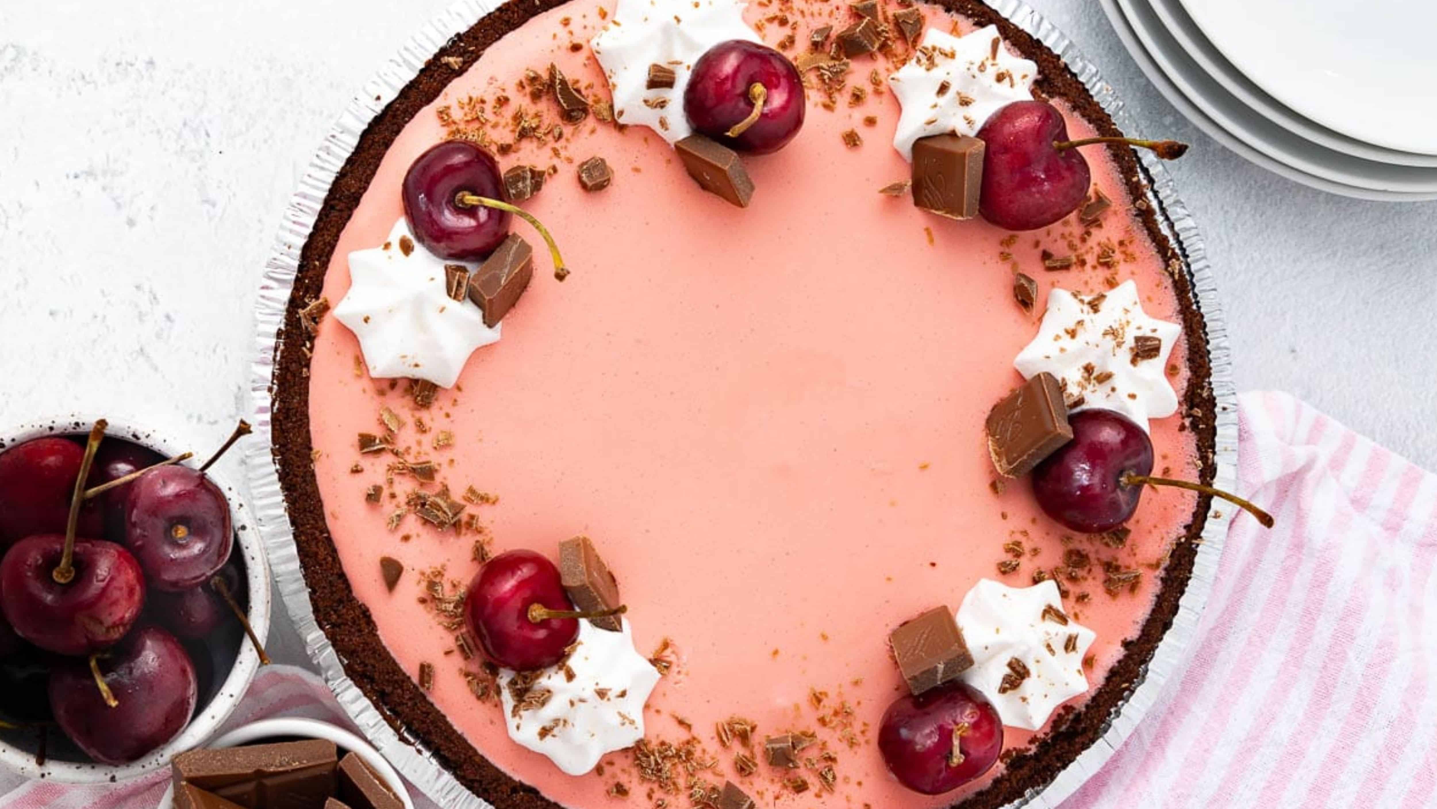 Pink cherry chocolate pie with whipped cream and chocolate shavings.