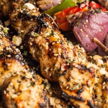 Grilled chicken skewers with herbs, served with roasted red onions, bell peppers, and spices.