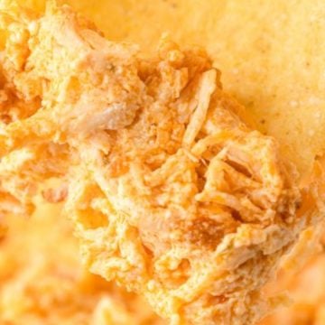 A tortilla chip scoops up creamy, shredded buffalo chicken dip—one of the best easy appetizers before dinner.