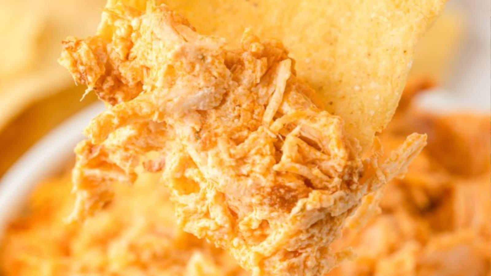 A tortilla chip scoops up creamy, shredded buffalo chicken dip—one of the best easy appetizers before dinner.