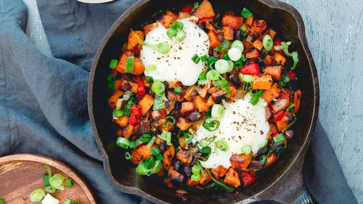 Crispy sweet potato hash cooked with vegetables in a skillet.