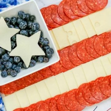 Charcuterie board with cheese, pepperoni, blueberries, and star-shaped cheese arranged like the American flag.