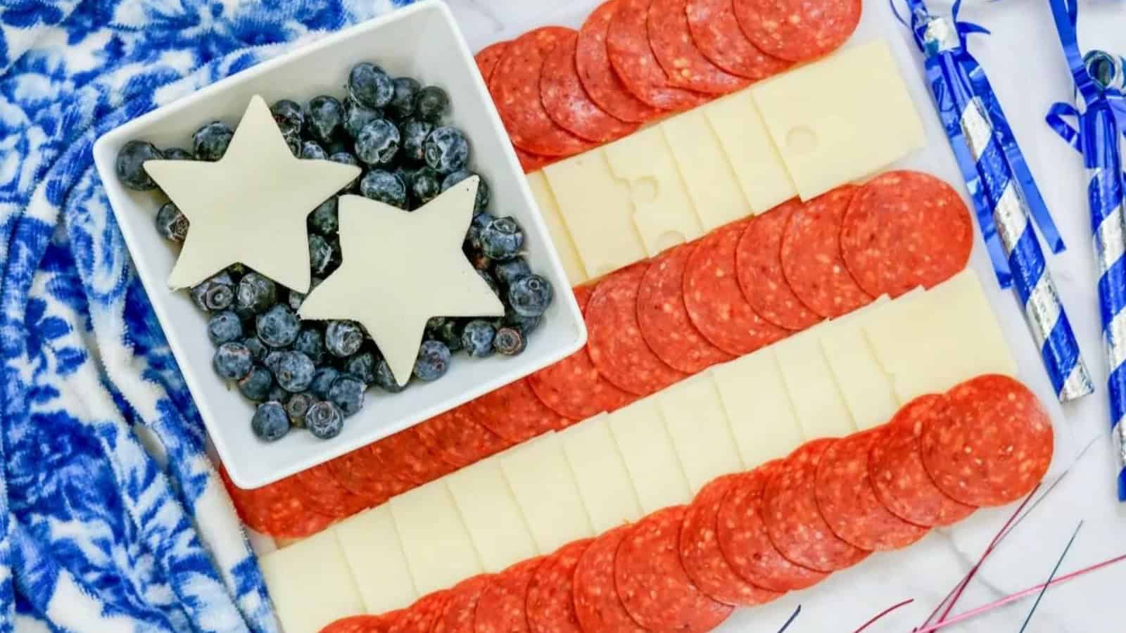 Charcuterie board with cheese, pepperoni, blueberries, and star-shaped cheese arranged like the American flag.