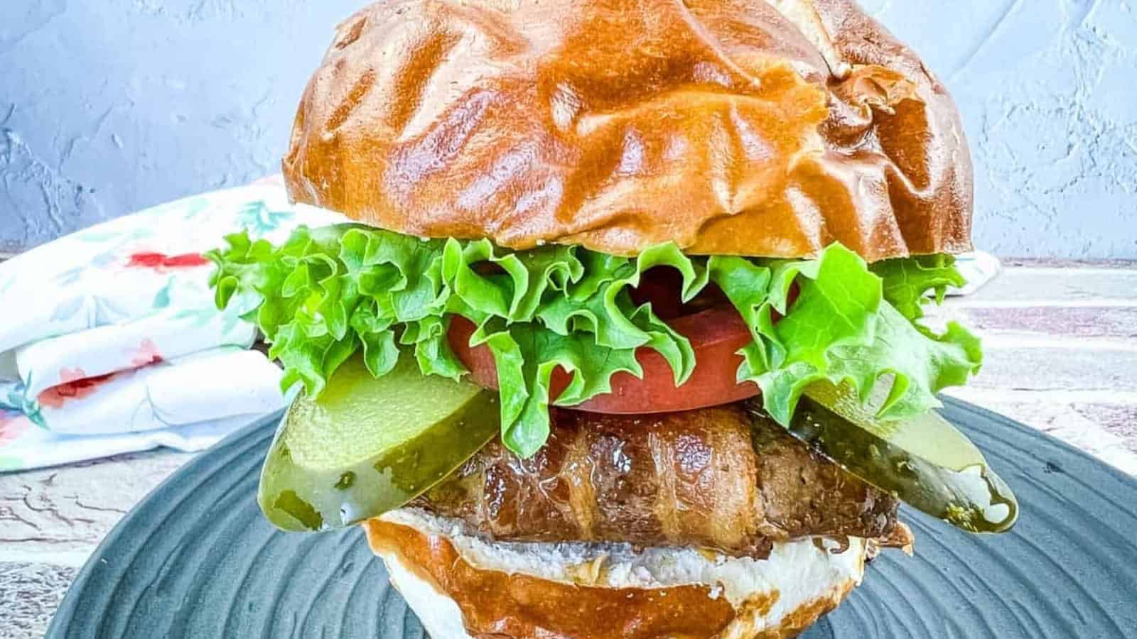 Bacon-Wrapped Burger on a black plate.