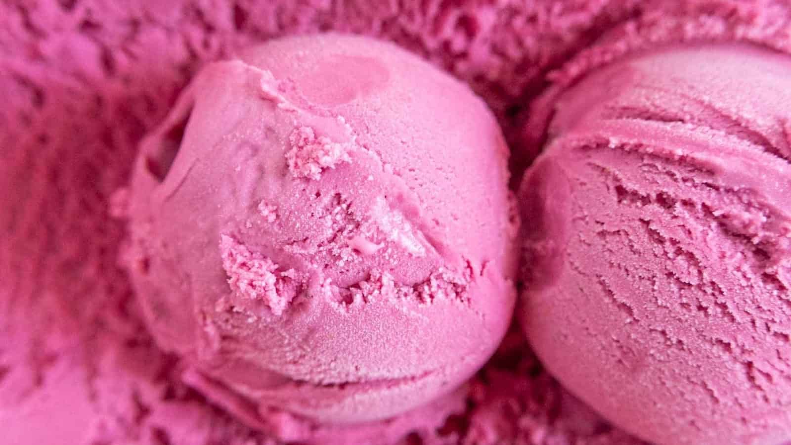 Close-up of two scoops of bright pink ice cream with a smooth, creamy texture.