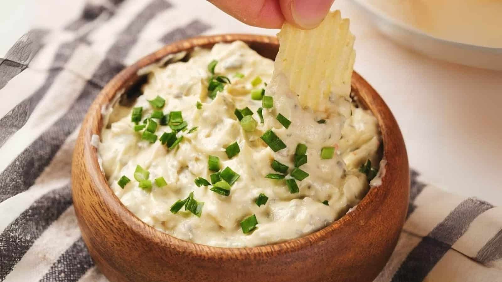 A bowl of chip dip garnished with chopped green onions.