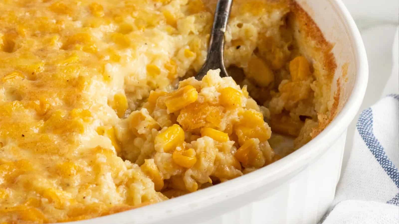 Classic corn pudding sliced in a baking dish with a spoonful removed.