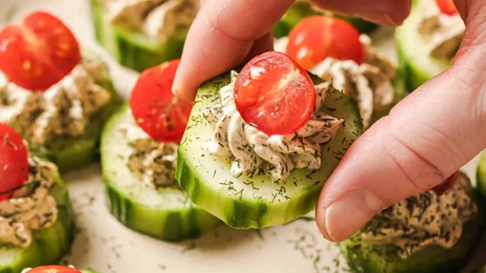 A hand holding a cucumber tomato bite.