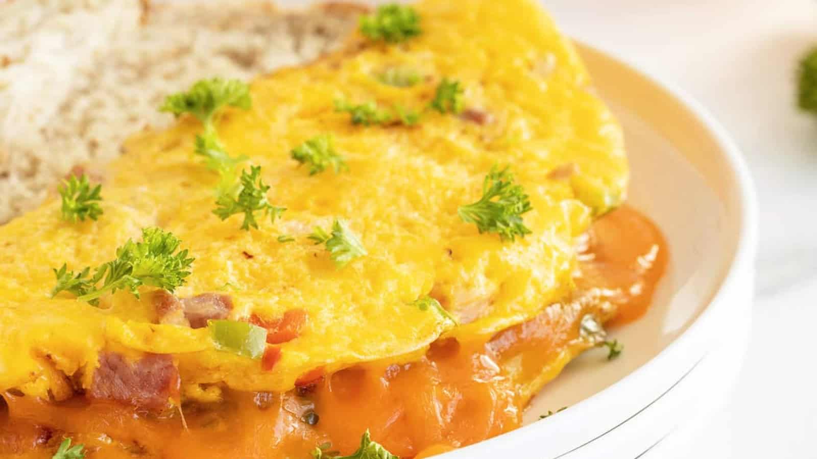 A cheese and vegetable omelette garnished with parsley, served with a slice of bread on a white plate.