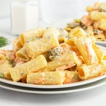 A plate of creamy pasta with herbs and vegetables, served on a white plate with forks nearby.