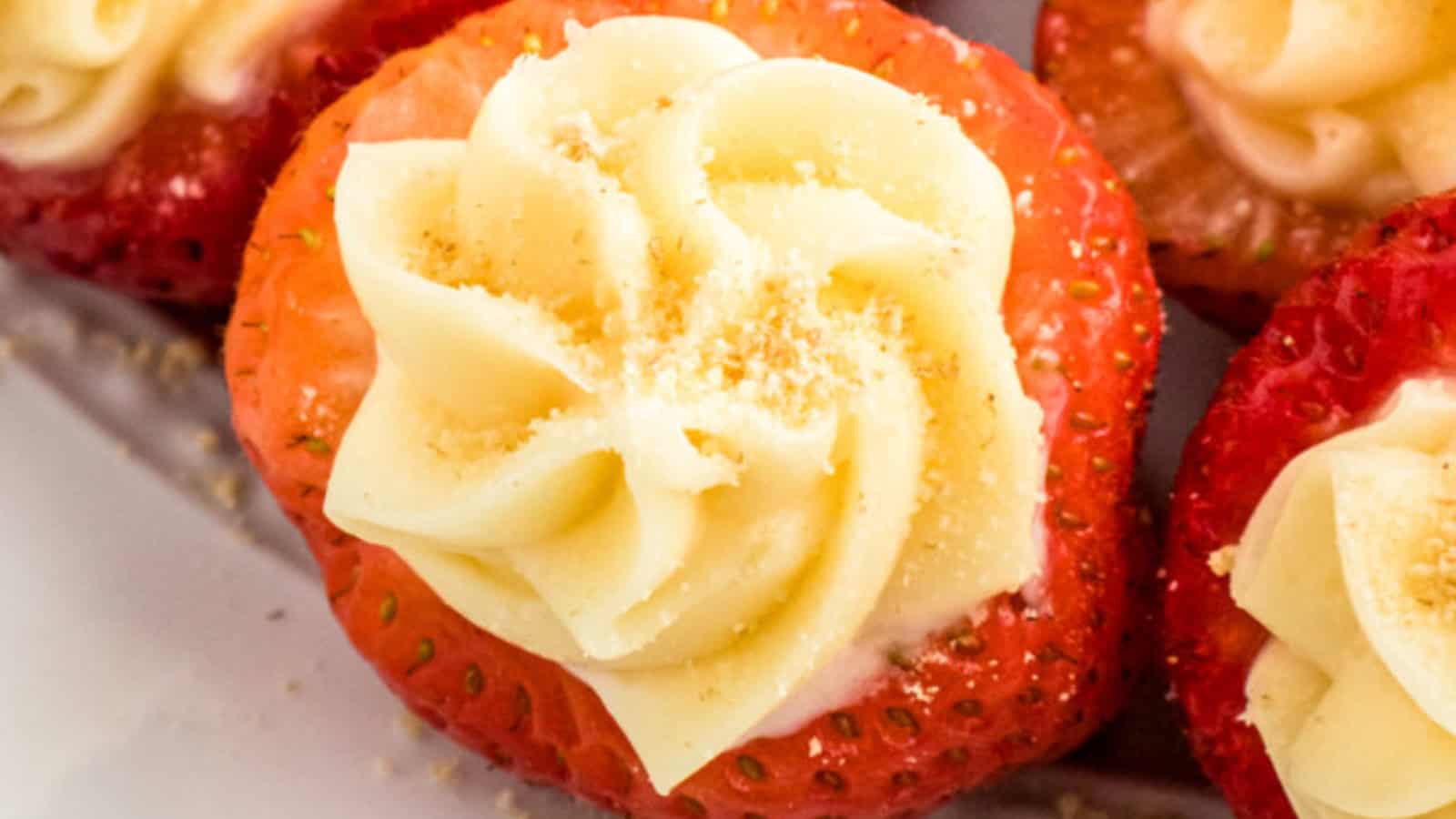 Close-up of strawberries filled with creamy frosting and sprinkled with crumbs on top.