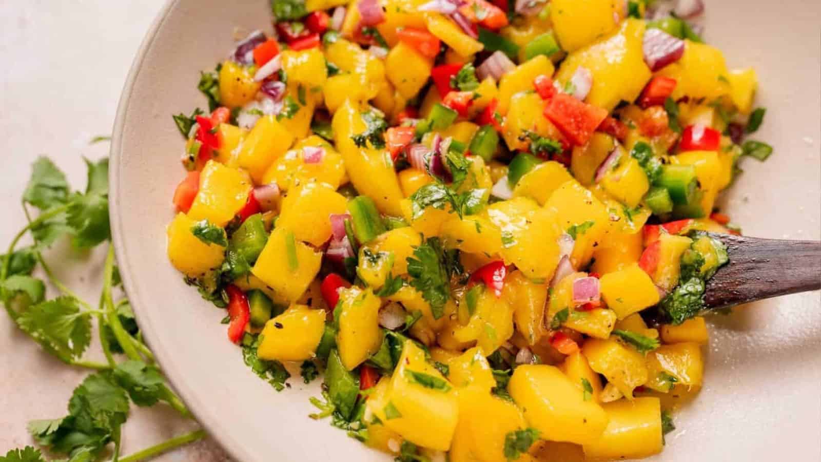 A bowl of fresh mango salsa with diced mango, red onion, red pepper, cilantro, and jalape&ntilde;o.