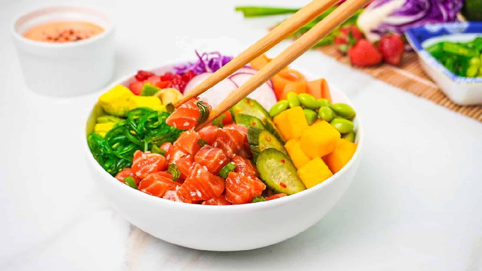 Salmon poke bowl topped with fresh vegetables, rice, and flavorful seasonings.