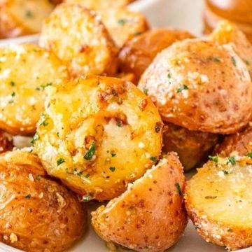 A plate of roasted baby potatoes garnished with herbs and grated cheese.