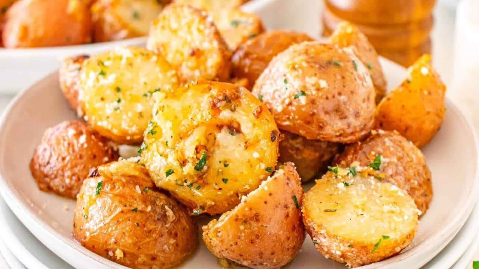 A plate of roasted baby potatoes garnished with herbs and grated cheese.