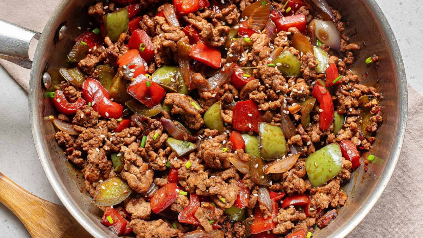 A bowl of beef stir fry with rice and peppers.