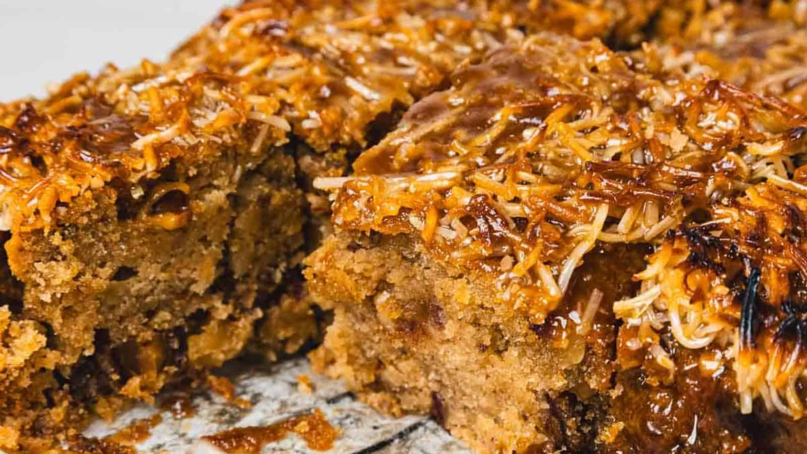 A close-up of moist, sliced coconut and caramel cake with a golden, toasted topping.