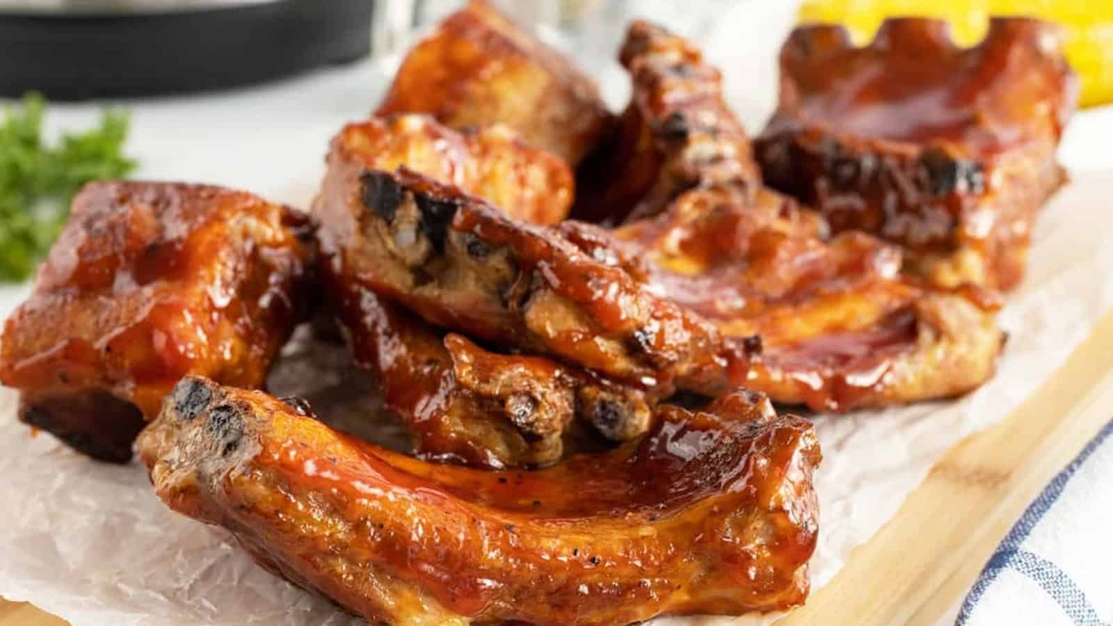 Barbecue pork ribs with a shiny glaze arranged on parchment paper, ready to be served.