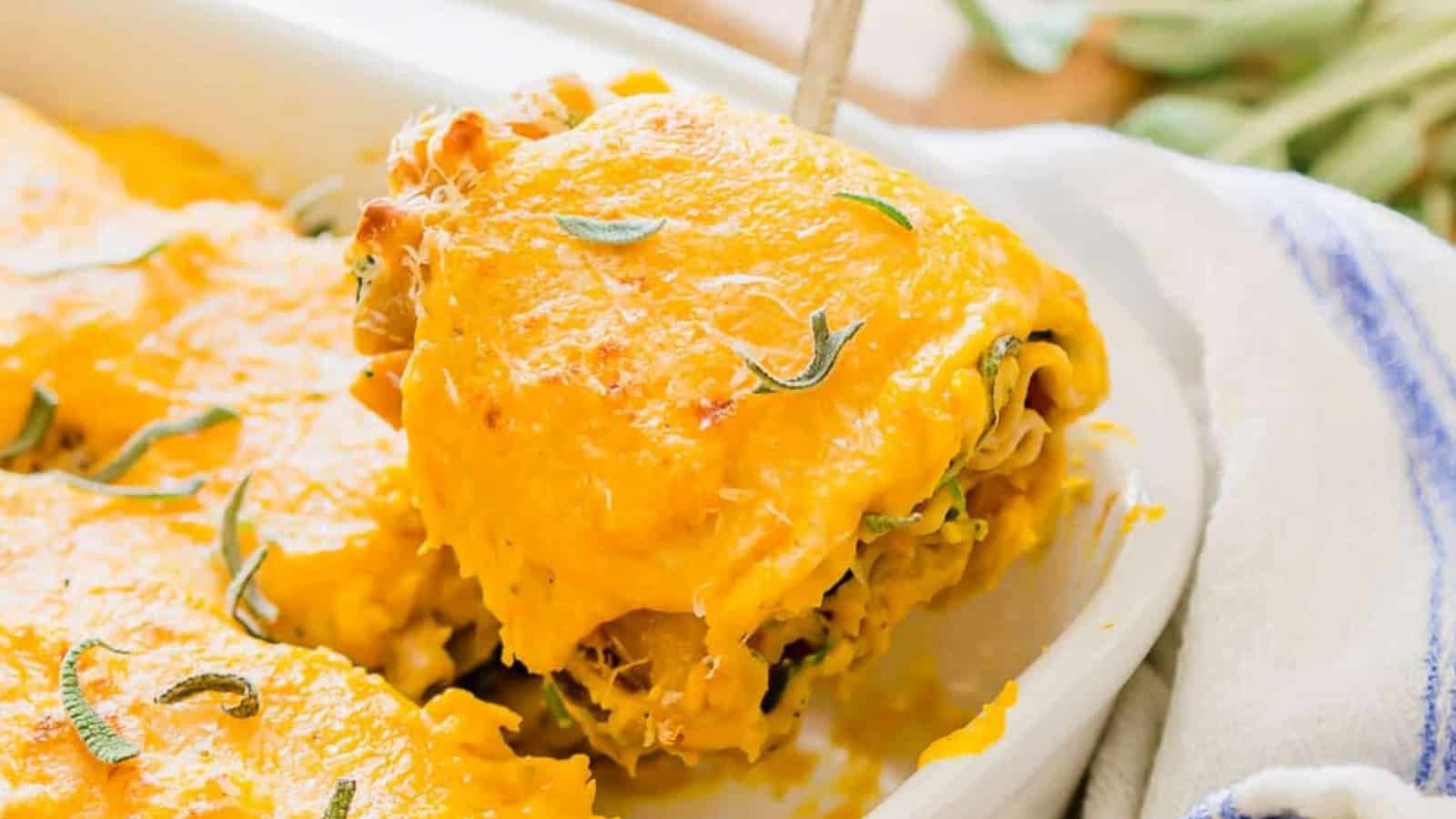 A slice of cheesy baked lasagna is being lifted from a casserole dish with a serving utensil.