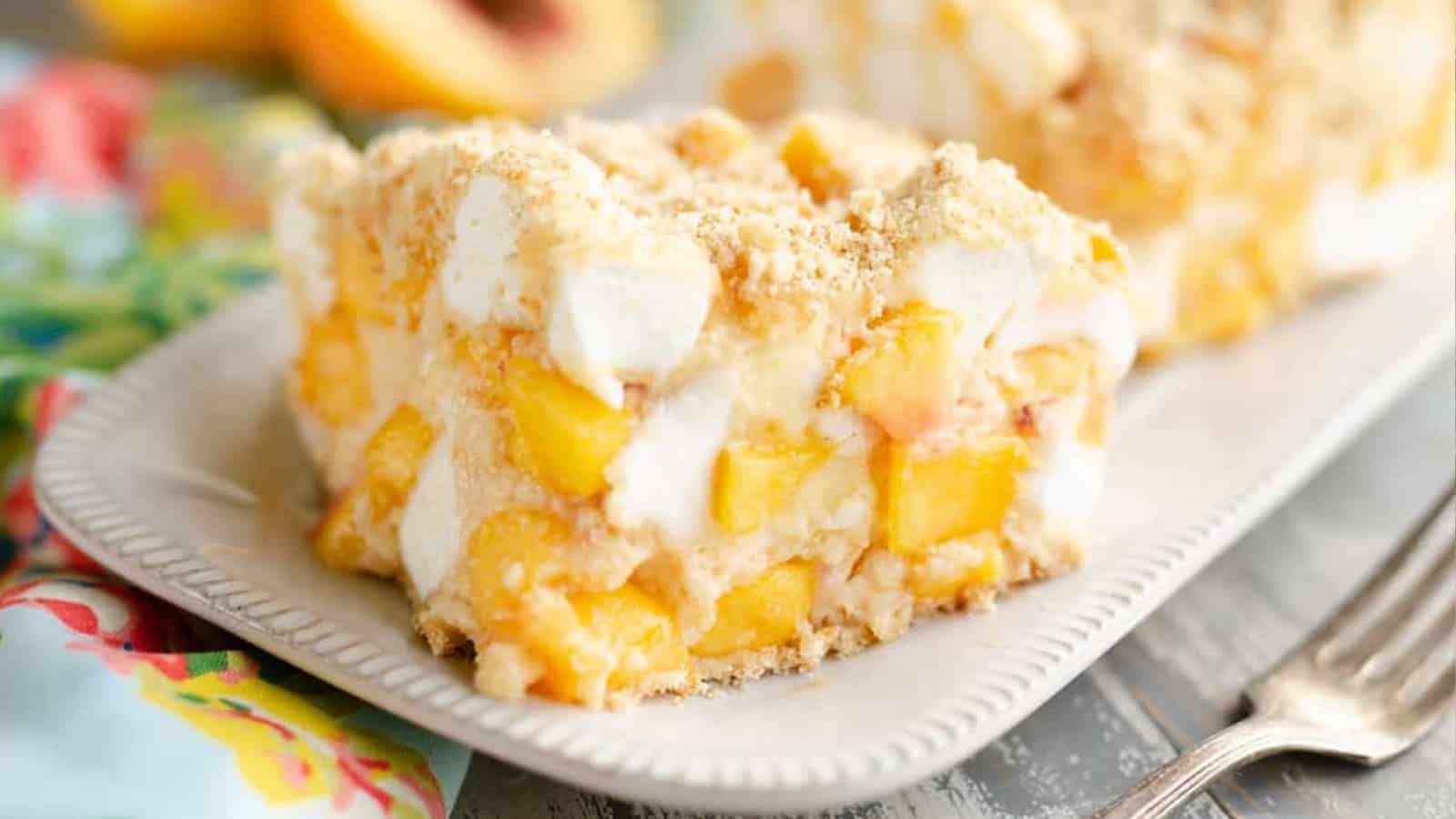 A slice of peach dessert with marshmallows and crumb topping on a white plate.