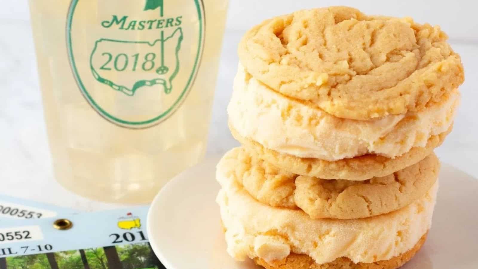 A stack of ice cream sandwiches sits on a plate next to a 2018 Masters cup and a tournament badge.