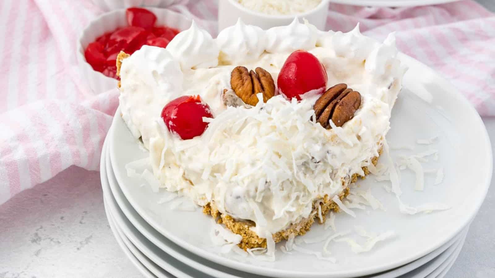 Millionaire pie slice filled with pineapple, cherries, and whipped cream in a graham crust.