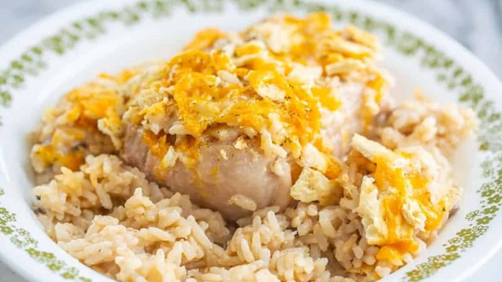 A plate of baked chicken and rice topped with melted cheese and crushed crackers.