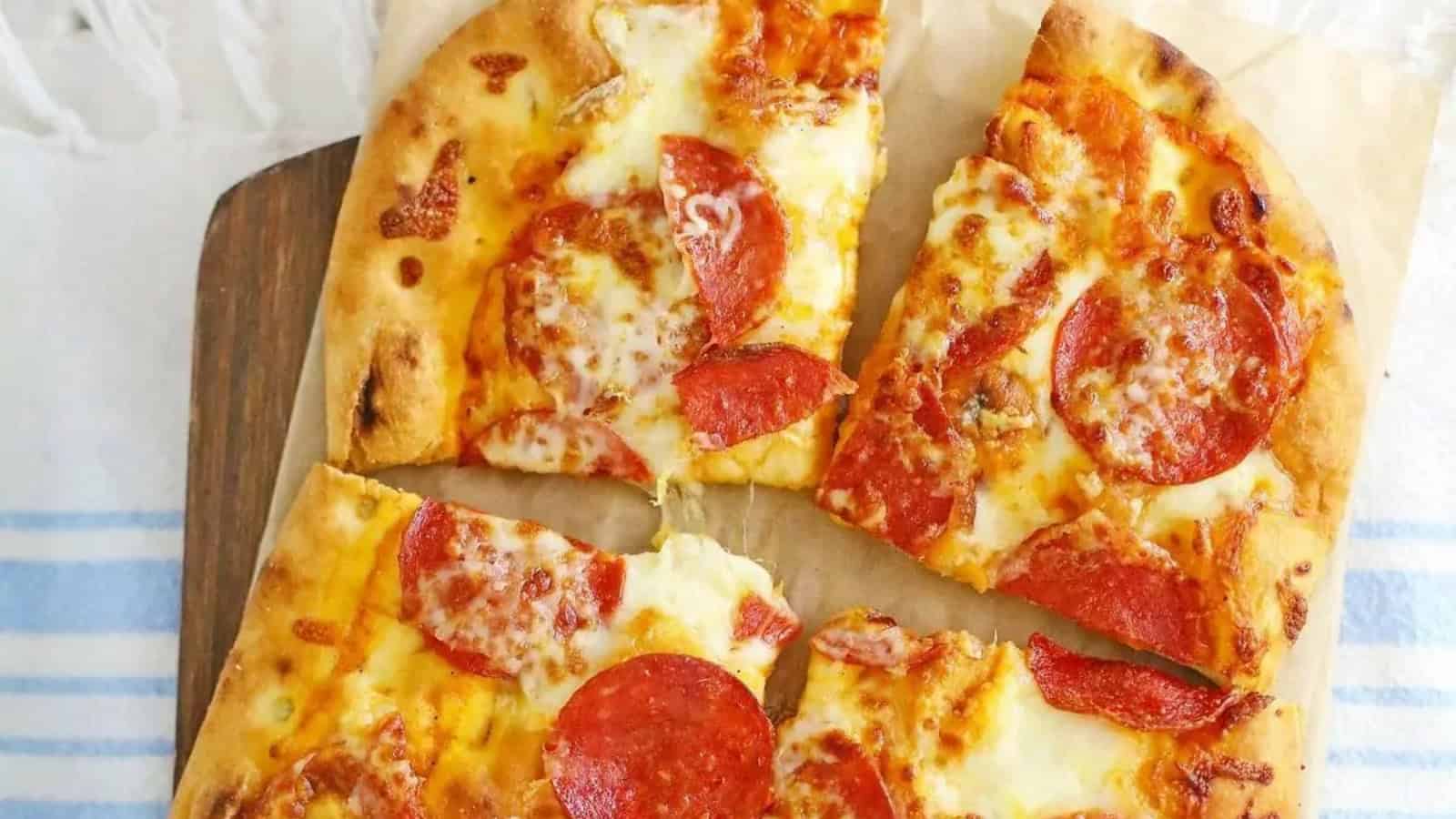 Four slices of pepperoni pizza with melted cheese on a wooden board.