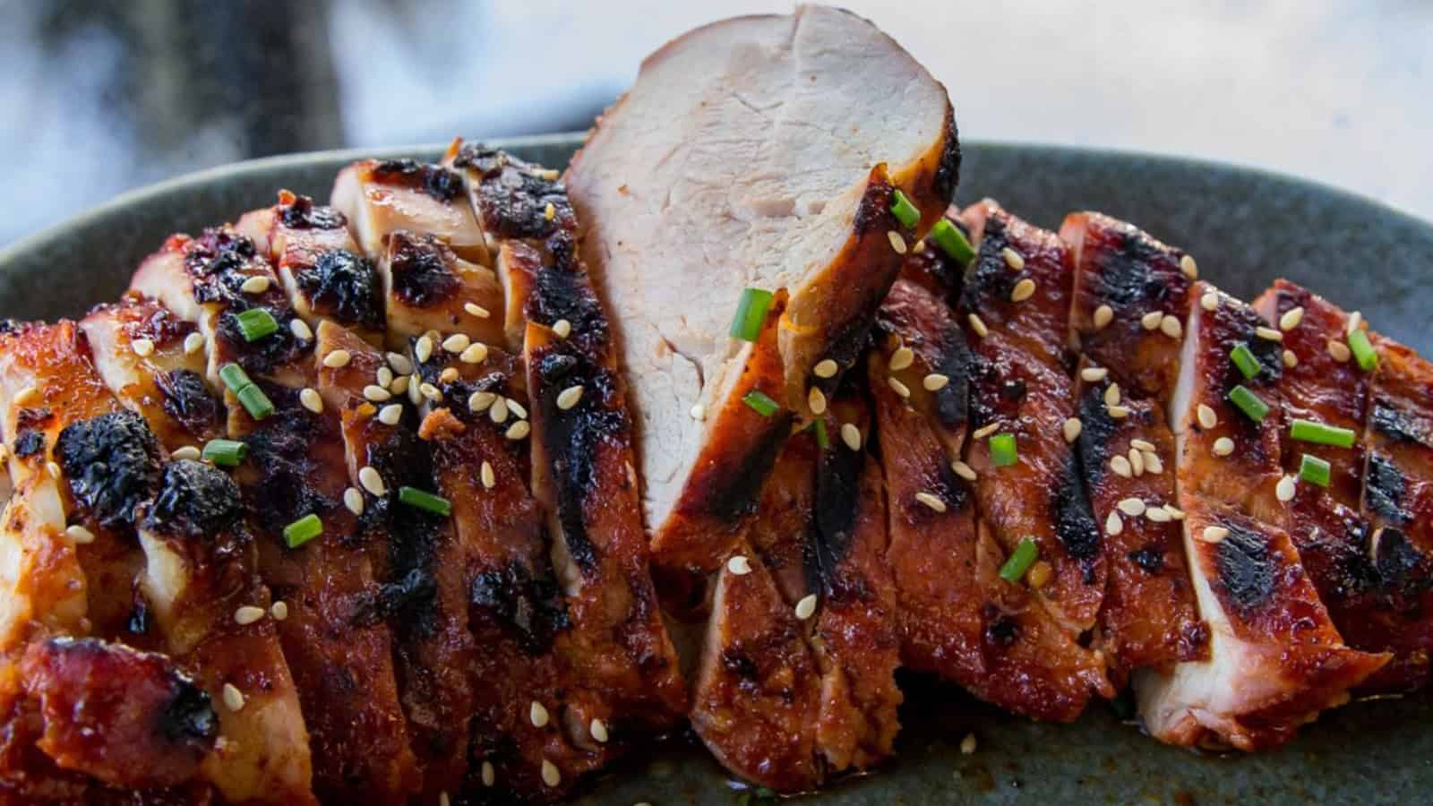 Grilled, sliced chicken breast topped with sesame seeds and chopped chives on a dark plate&mdash;perfect for your Father's Day BBQ recipes or to throw on the grill anytime.