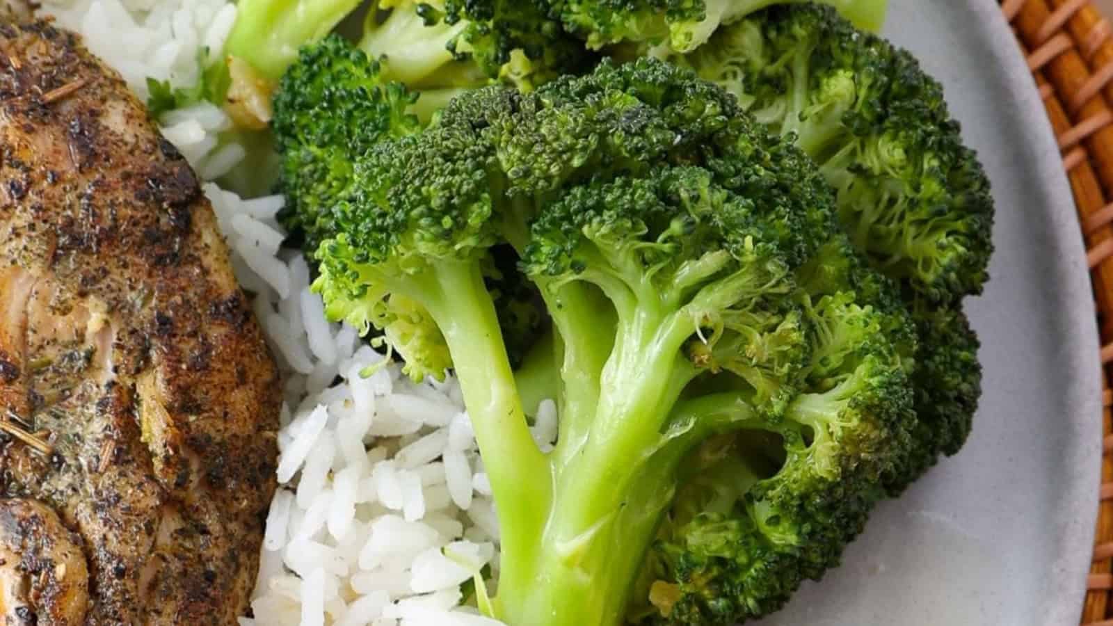 Steamed broccoli served with white rice and a portion of seasoned grilled chicken on a plate.