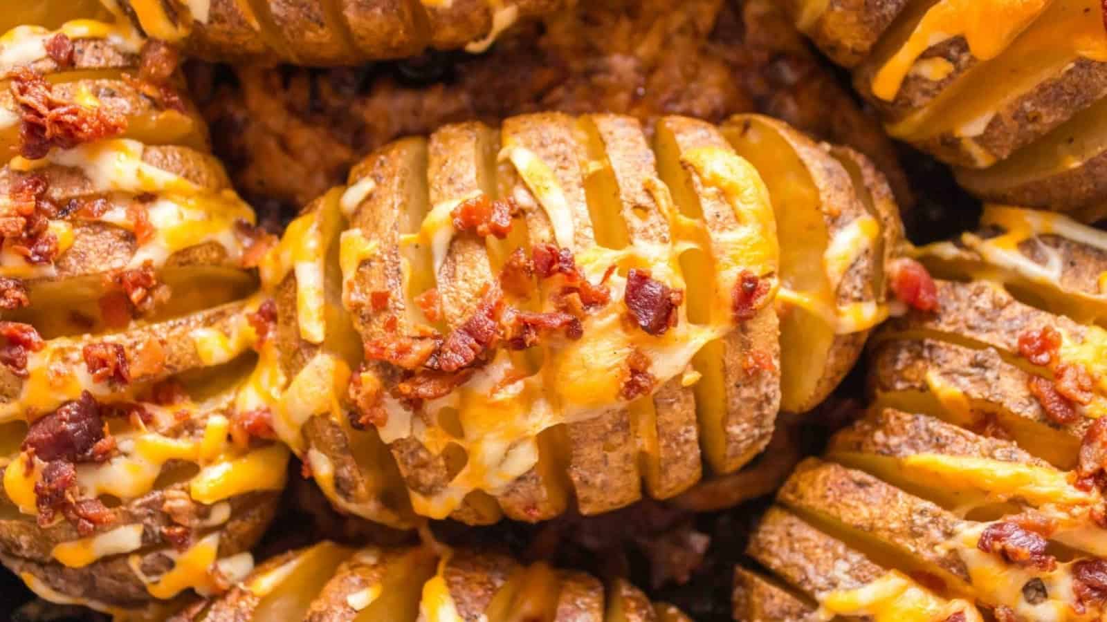 Hasselback potatoes topped with melted cheese and crispy bacon pieces.