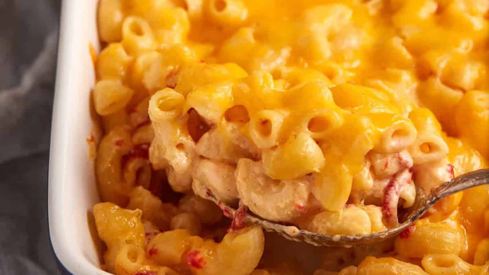 Close-up of baked macaroni and cheese in a dish, with a spoon lifting out a cheesy serving.