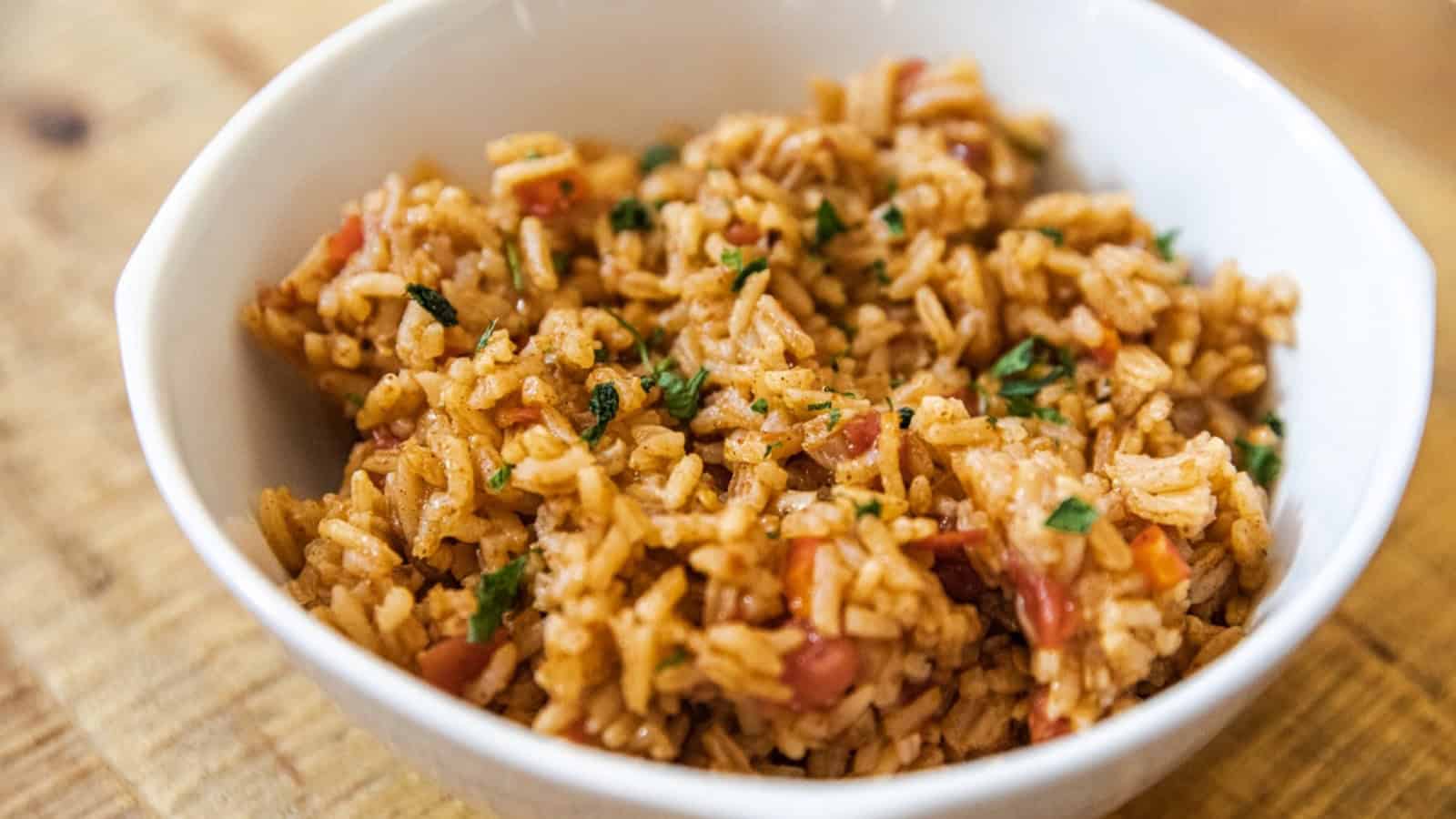 Spanish rice served in a white bowl with herbs and diced vegetables.
