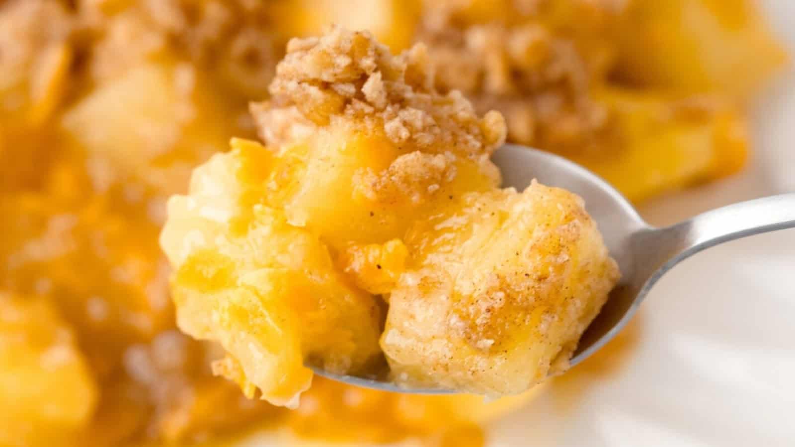 A spoonful of apple crumble with baked apples and a crumbly cinnamon topping.