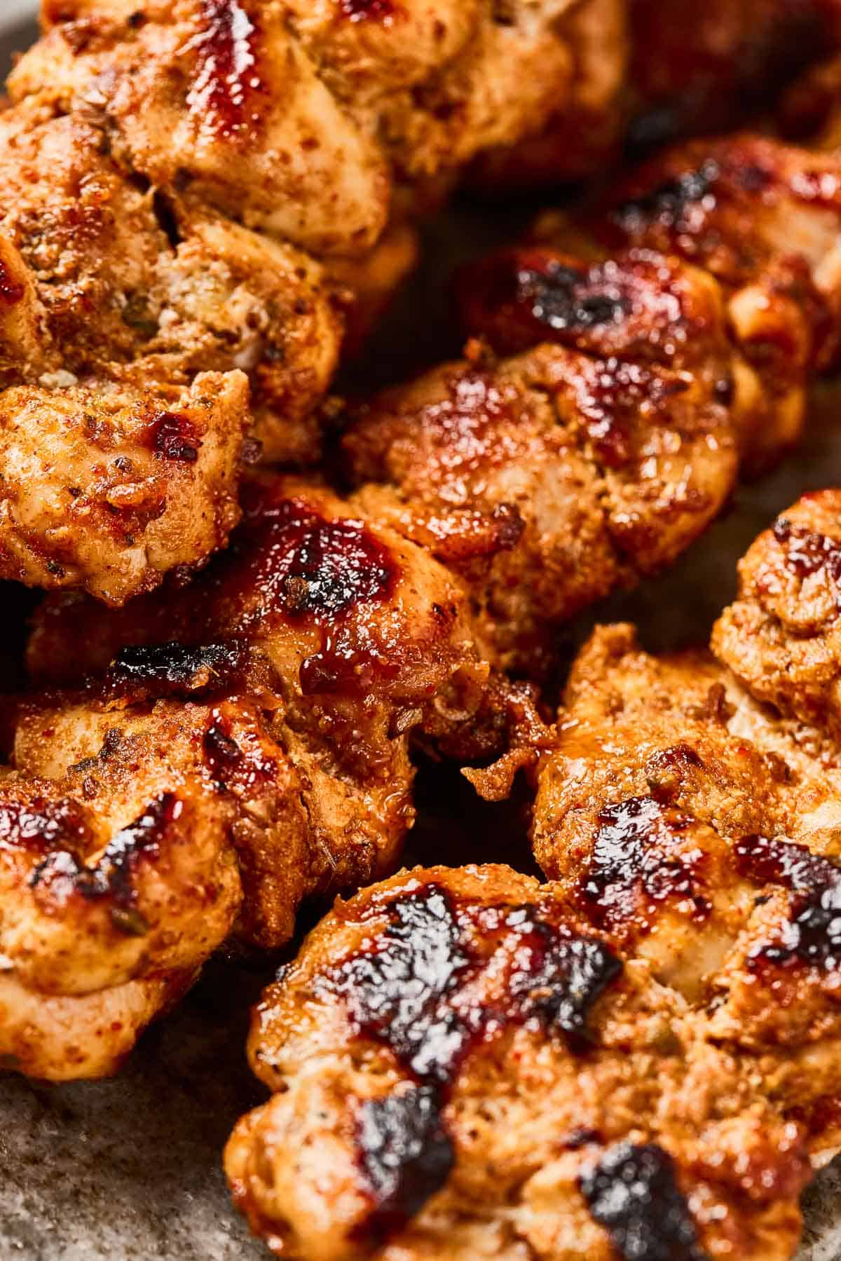 Close-up of grilled, charred, and seasoned chicken pieces with a golden-brown, crispy exterior.