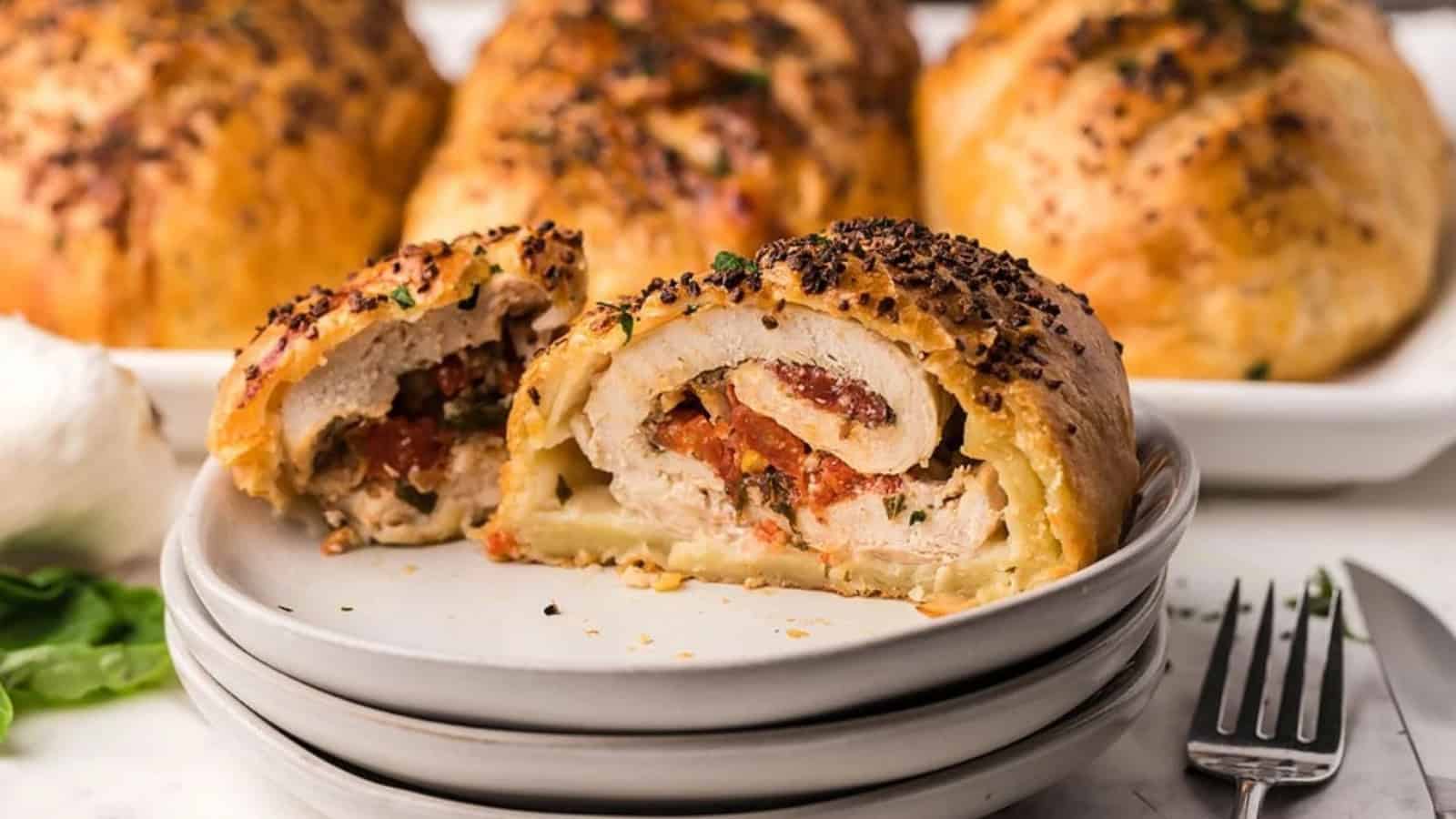 A stuffed pastry cut open on a plate, showing a filling of meat and vegetables, with more pastries in the background.