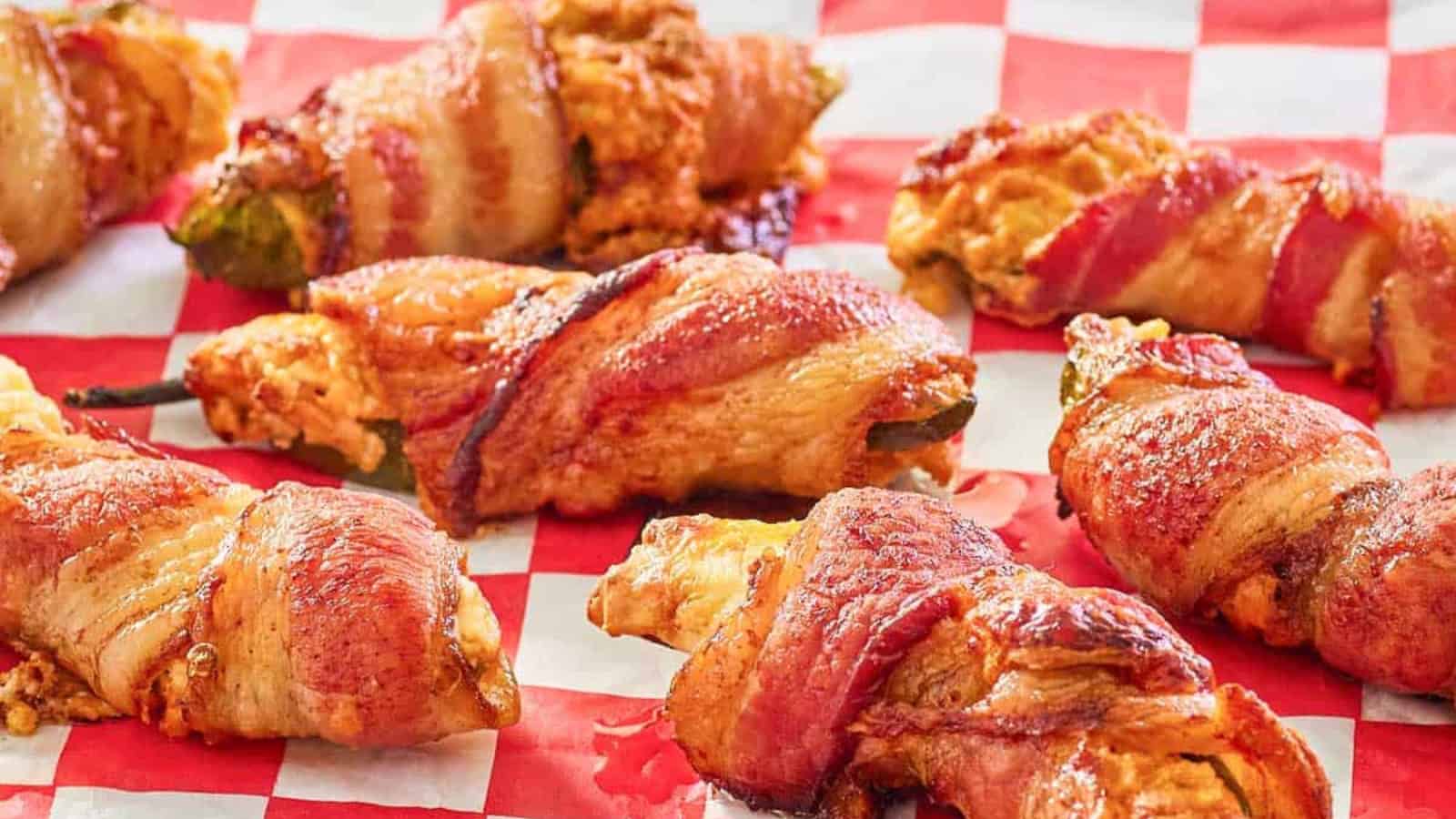 Bacon-wrapped jalape&ntilde;o poppers on a red and white checkered surface.