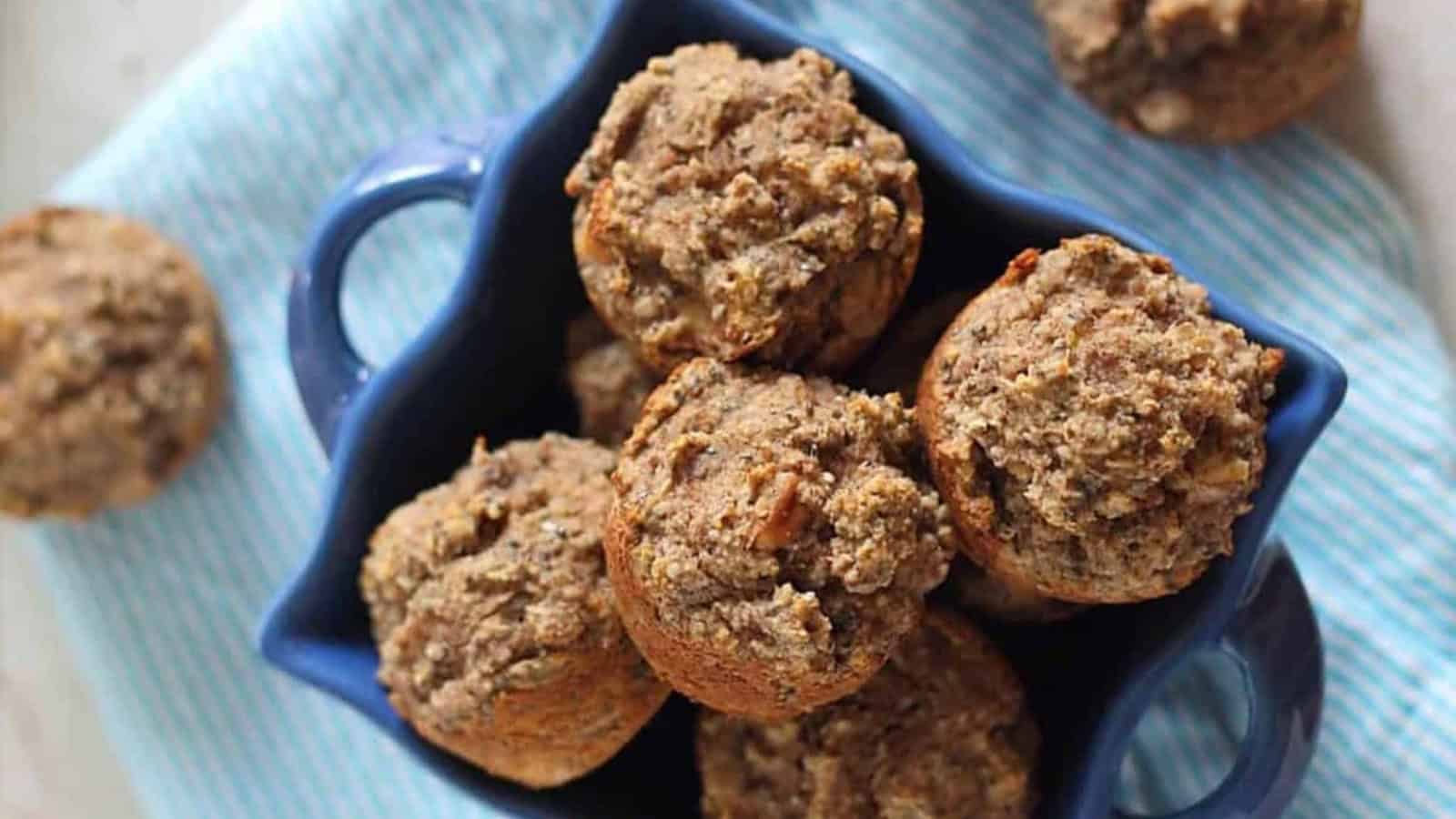A blue dish filled with several homemade muffins on a blue-striped cloth.