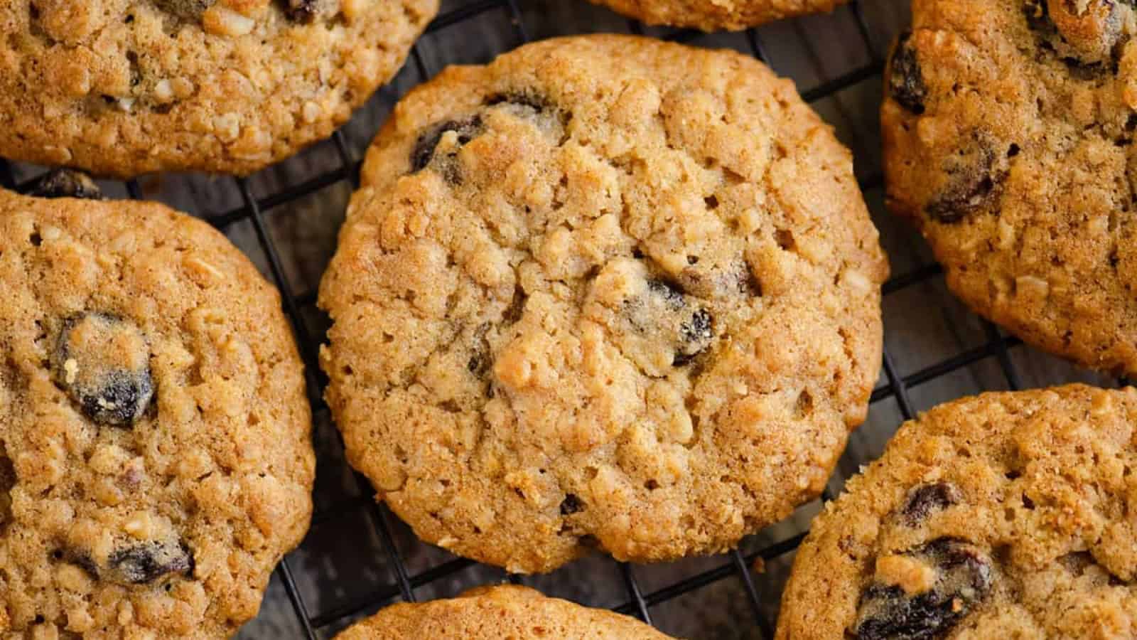 Oatmeal raisin cookies cooling on a black wire rack, showing their texture and visible raisins.