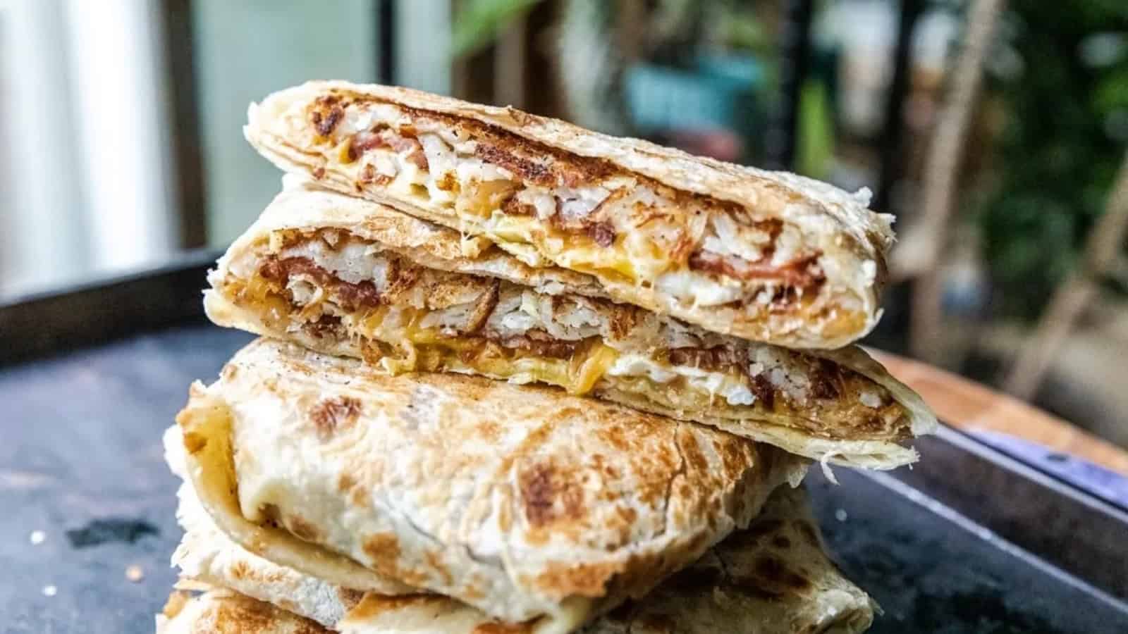 Stacked grilled wraps with crispy edges, filled with cheese, meat, and eggs, shown in close-up.